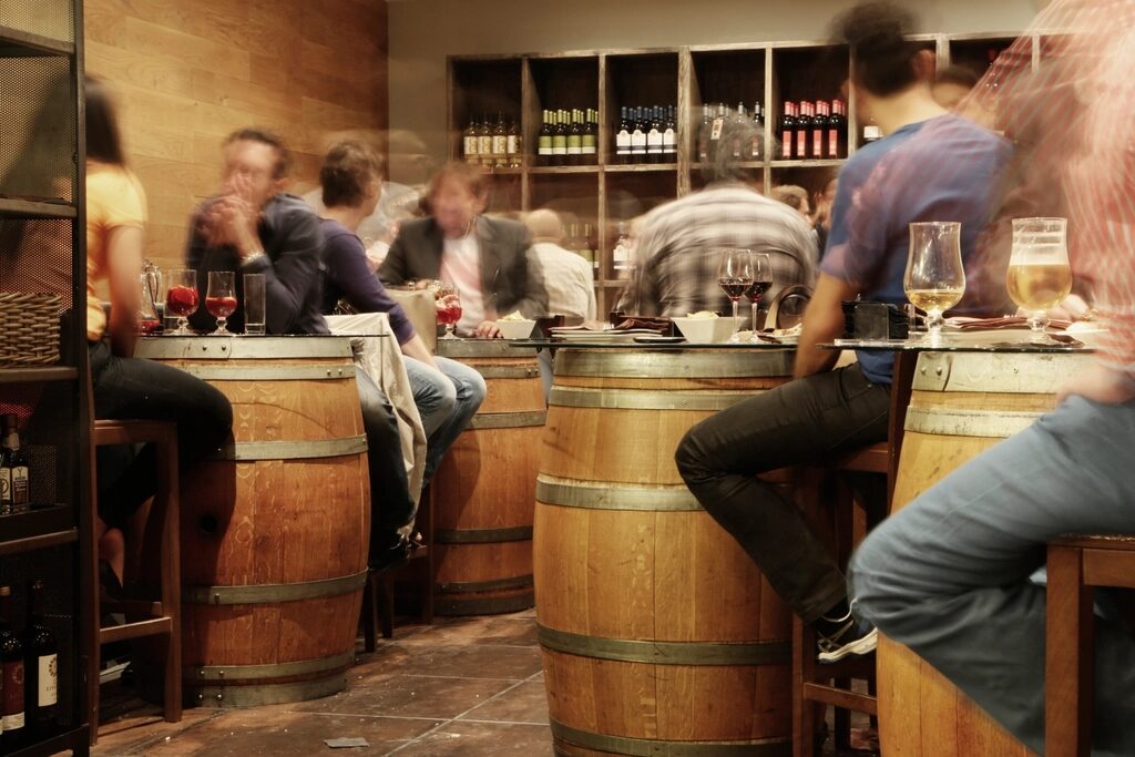 Guests seated at barrel tables inside a warmly lit pub